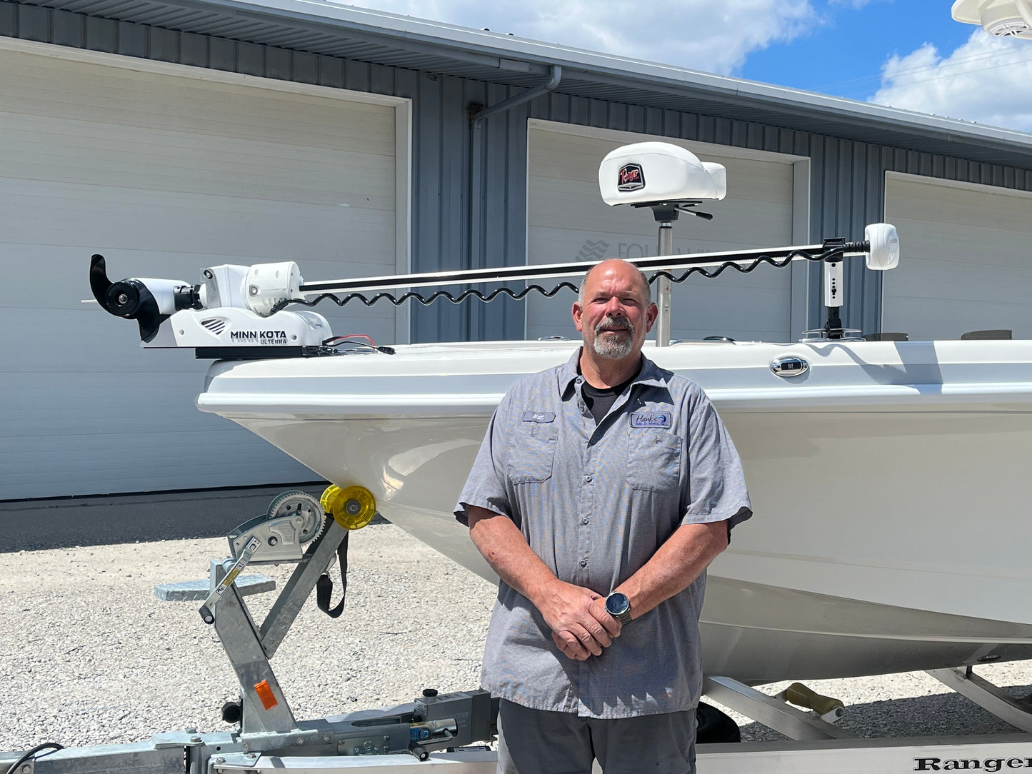 White Staymo shock absorber/stabilizer pictured supporting a trolling motor attached to the boat deck and man standing in front of boat.